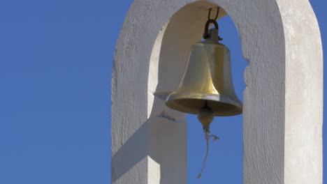 on a semicircular concrete arch hangs a bell and swinging in the wind