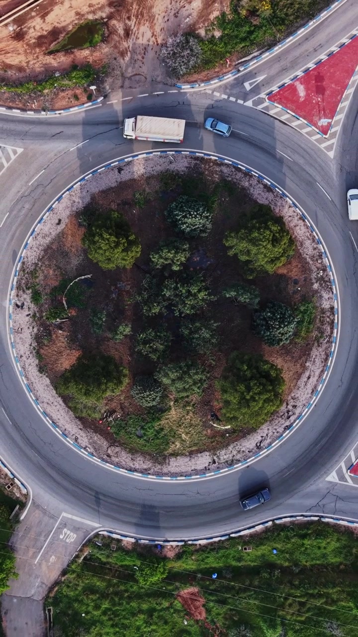Top down aerial view of a road roundabout with green trees