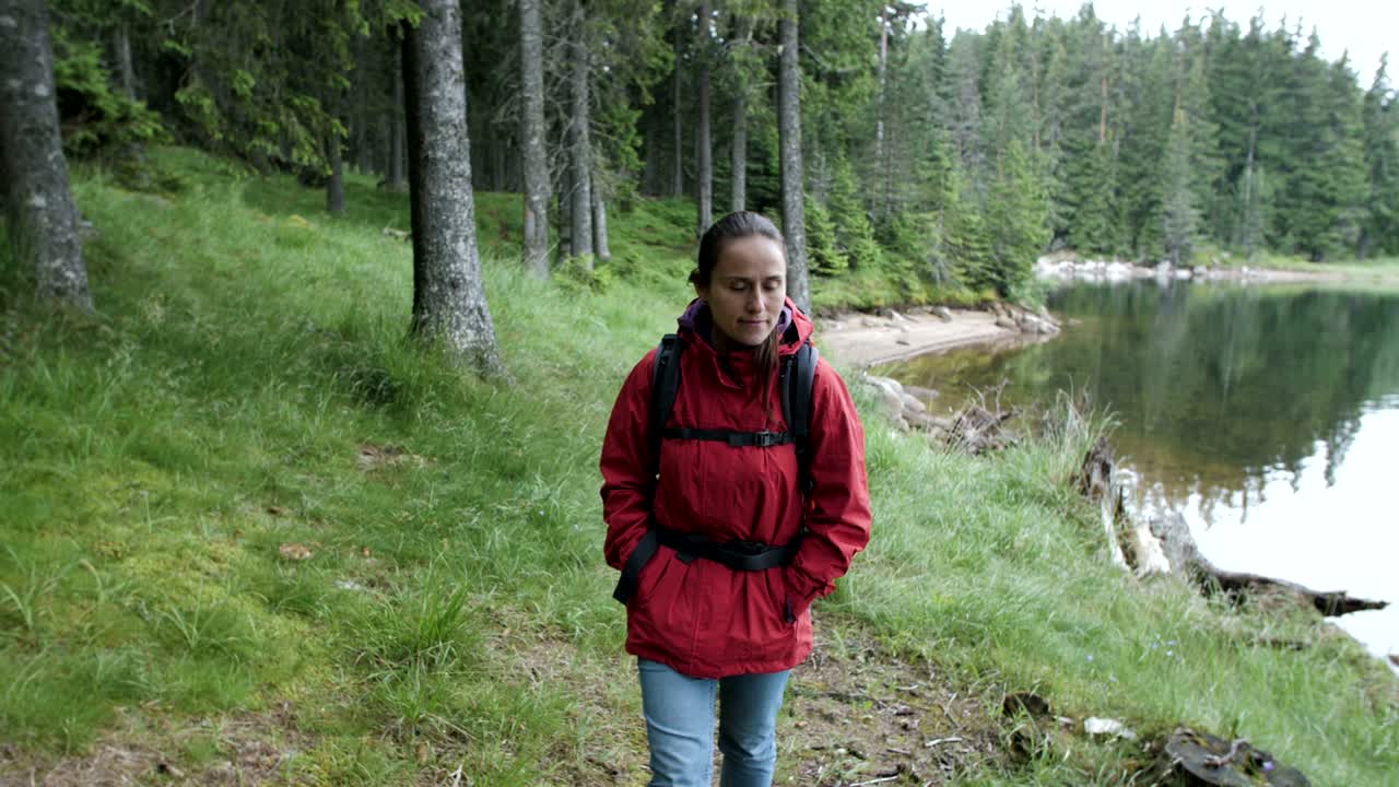 Sakte film av en ung turistkvinne som går forbi en innsjø