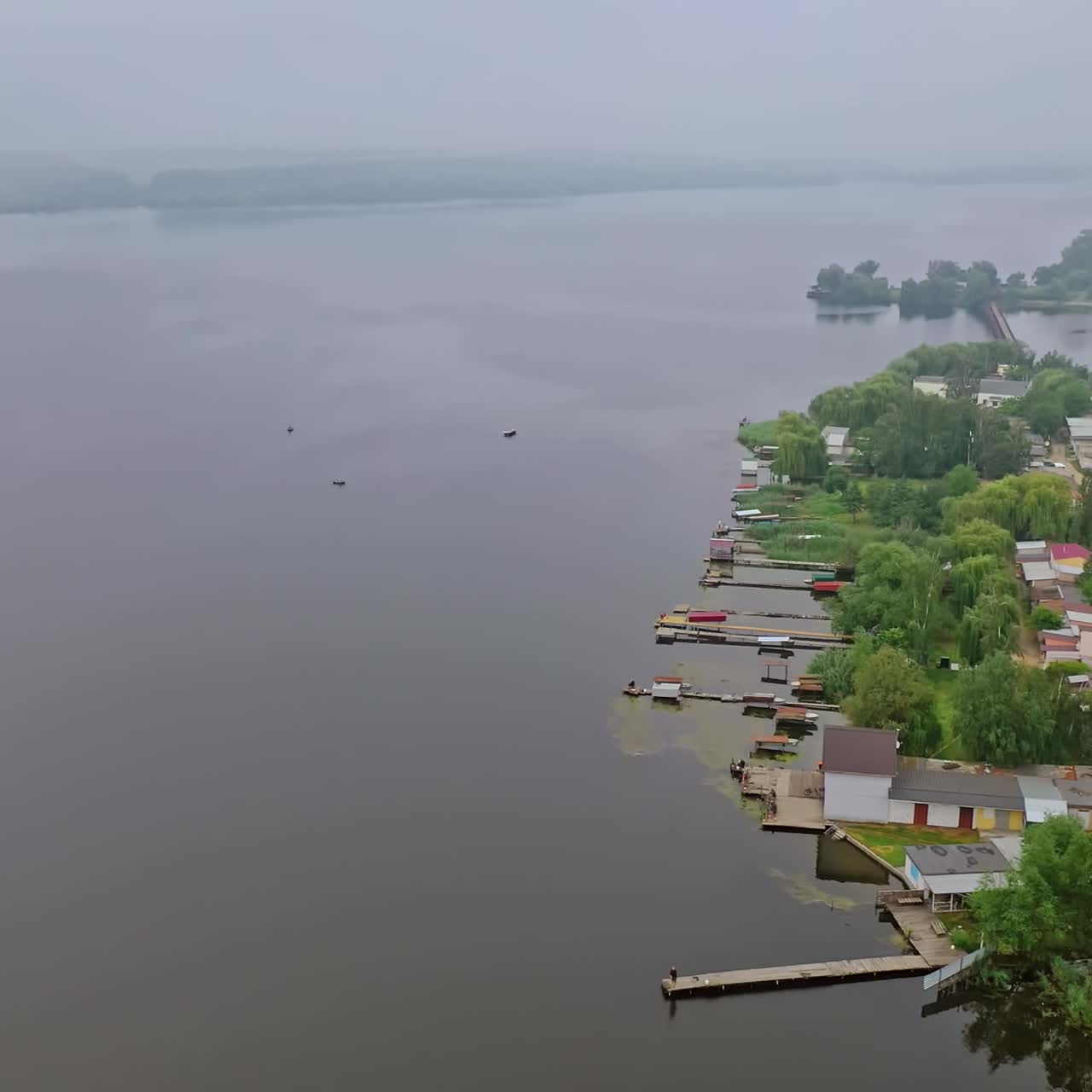 High voltage lines near the river. Electric towers in the countryside on water background. Power transmission lines in nature. Aerial view.