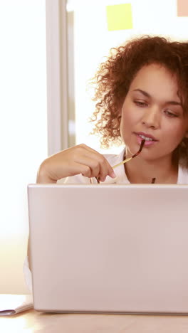 mujer de negocios casual sonriente usando una computadora portátil