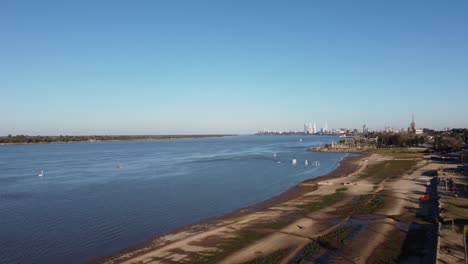 hermosa puesta de sol de barcos a lo largo del río con la ciudad al fondo bajo un cielo azul