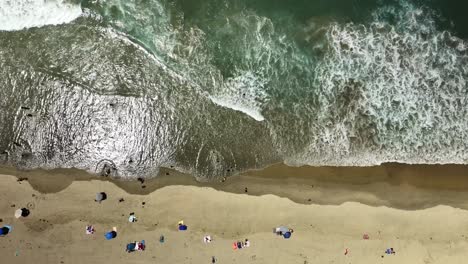 Vista-Aérea-Hacia-Abajo-De-Las-Olas,-Surf,-Arena-Y-Gente-En-Huntington-Beach,-California.