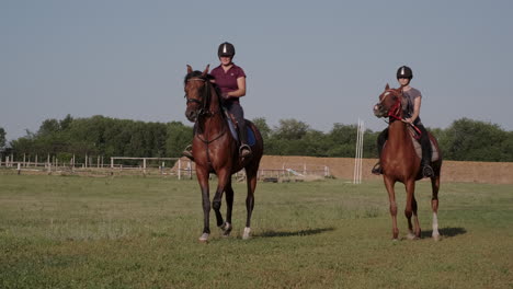 two women horse riding in a field