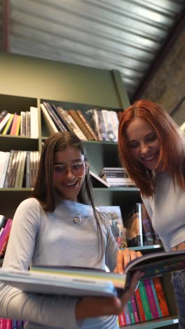 two young women in a library reading magazines