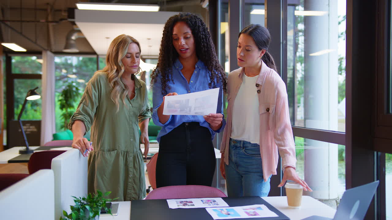 reunión del equipo de negocios femenino en el escritorio en una oficina de plan abierto que aprueba pruebas de verificación o diseños de diseño