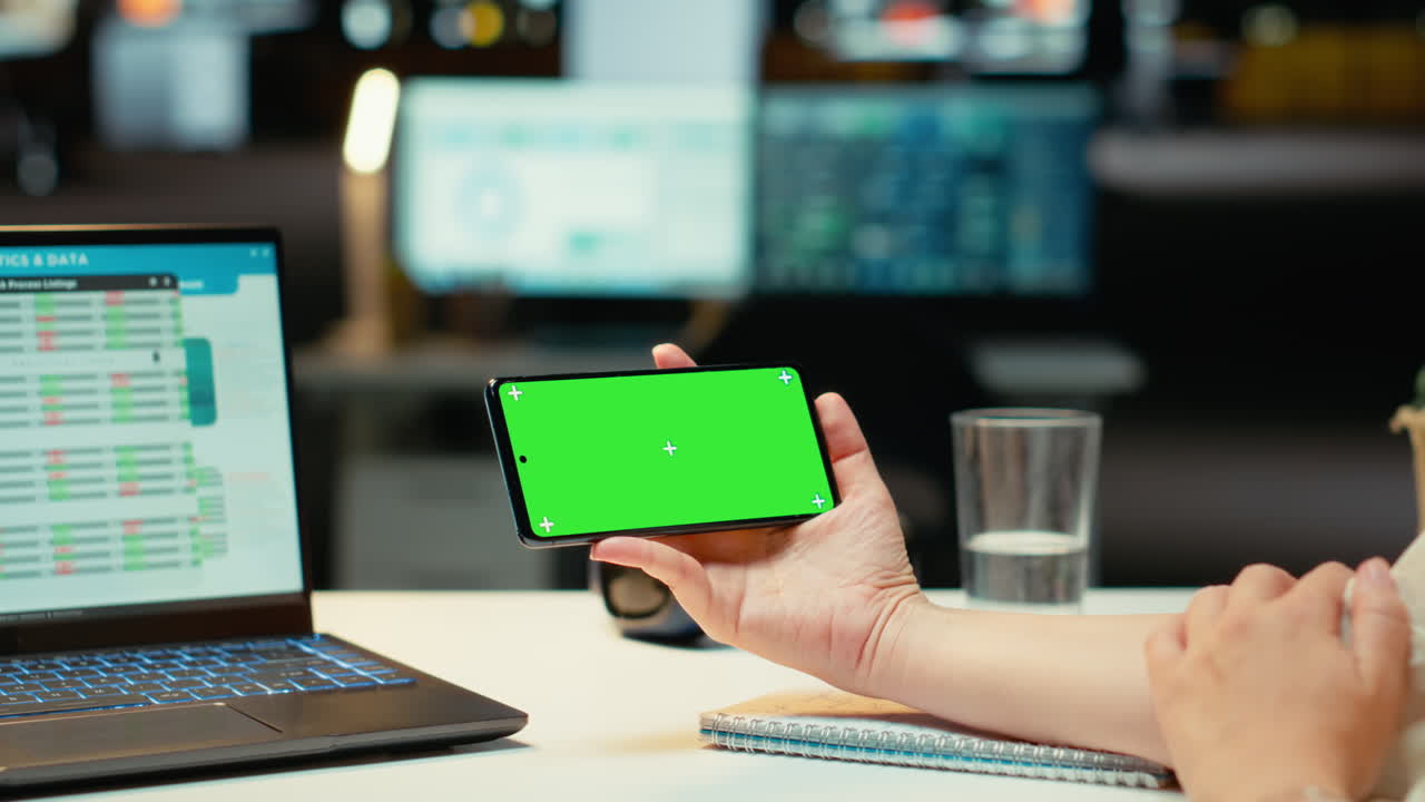 Businesswoman looking at green screen on mobile phone during work session