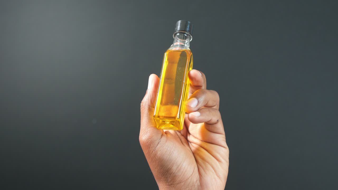 mano sosteniendo una pequeña botella de líquido amarillo