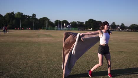 Woman-shaking-off-blanket-from-the-grass-and-running-towards-the-camera-to-show-her-happiness