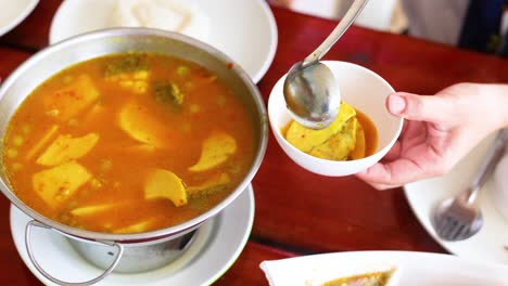 ladling curry into a bowl at restaurant