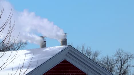 a couple round shaped household chimneys releasing white smoke into the air