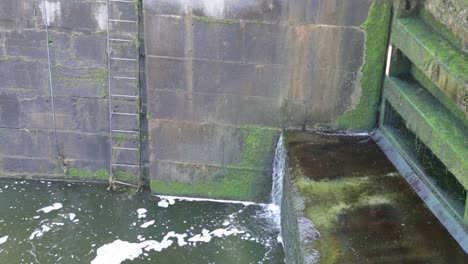 close-up-water-running-dirty-moss-sewer-waterfall