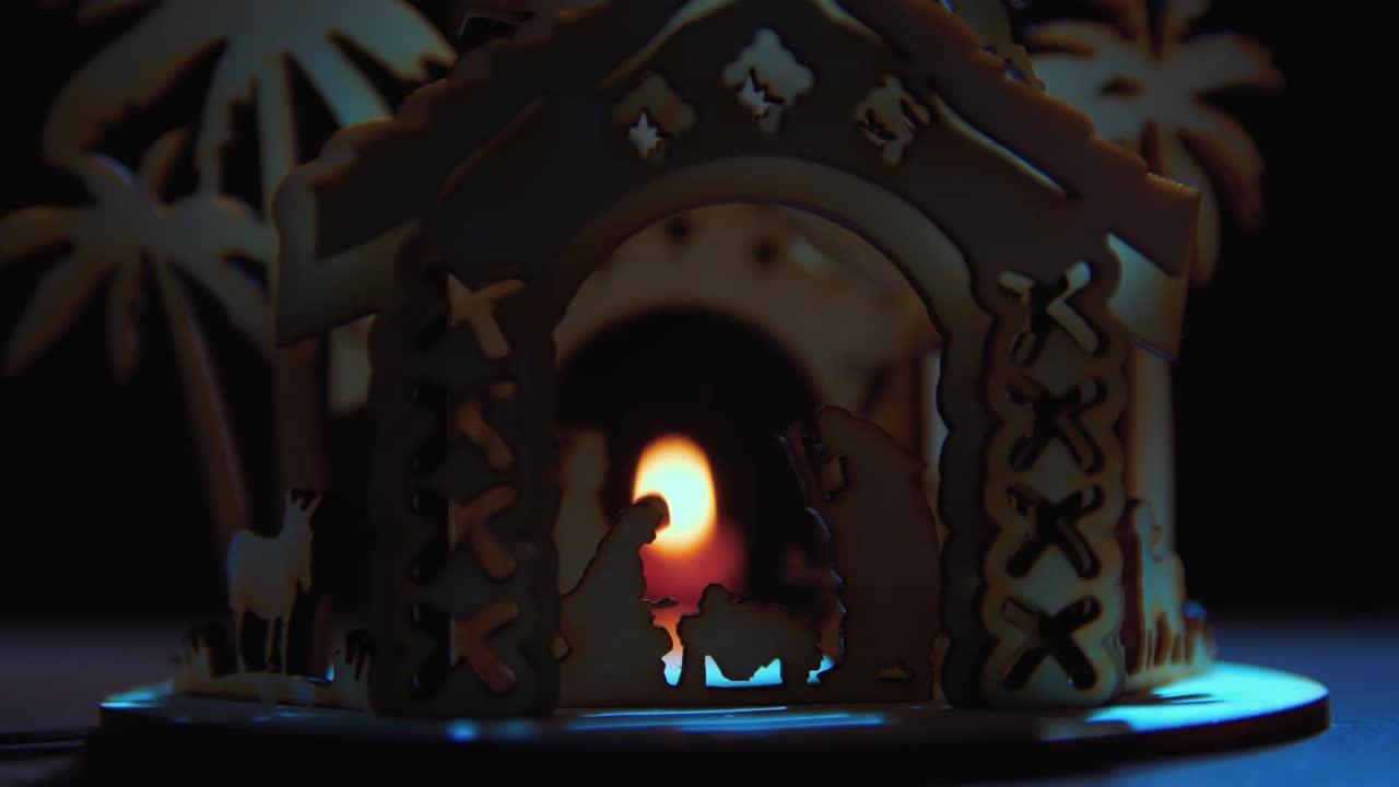 wooden betlehem on table with rotating view, with candle behind