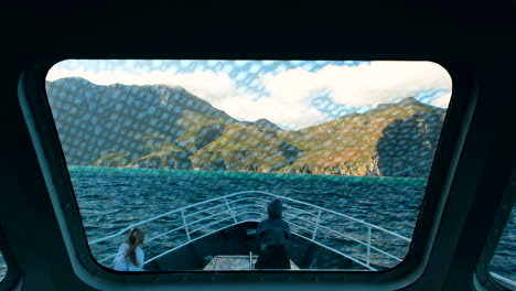 Scenic-boat-tour-in-Hout-Bay,-view-from-inside-cabin-of-mountains-over-ocean