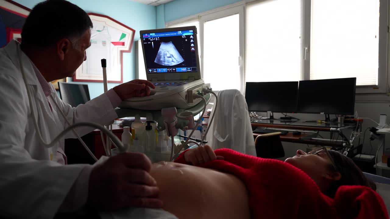 Gynecologist using ultrasound to check baby's feet of a pregnant woman