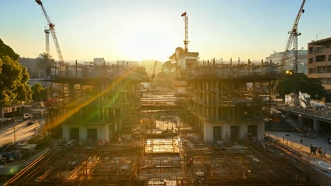 construction site at sunset with workers and cranes in the background