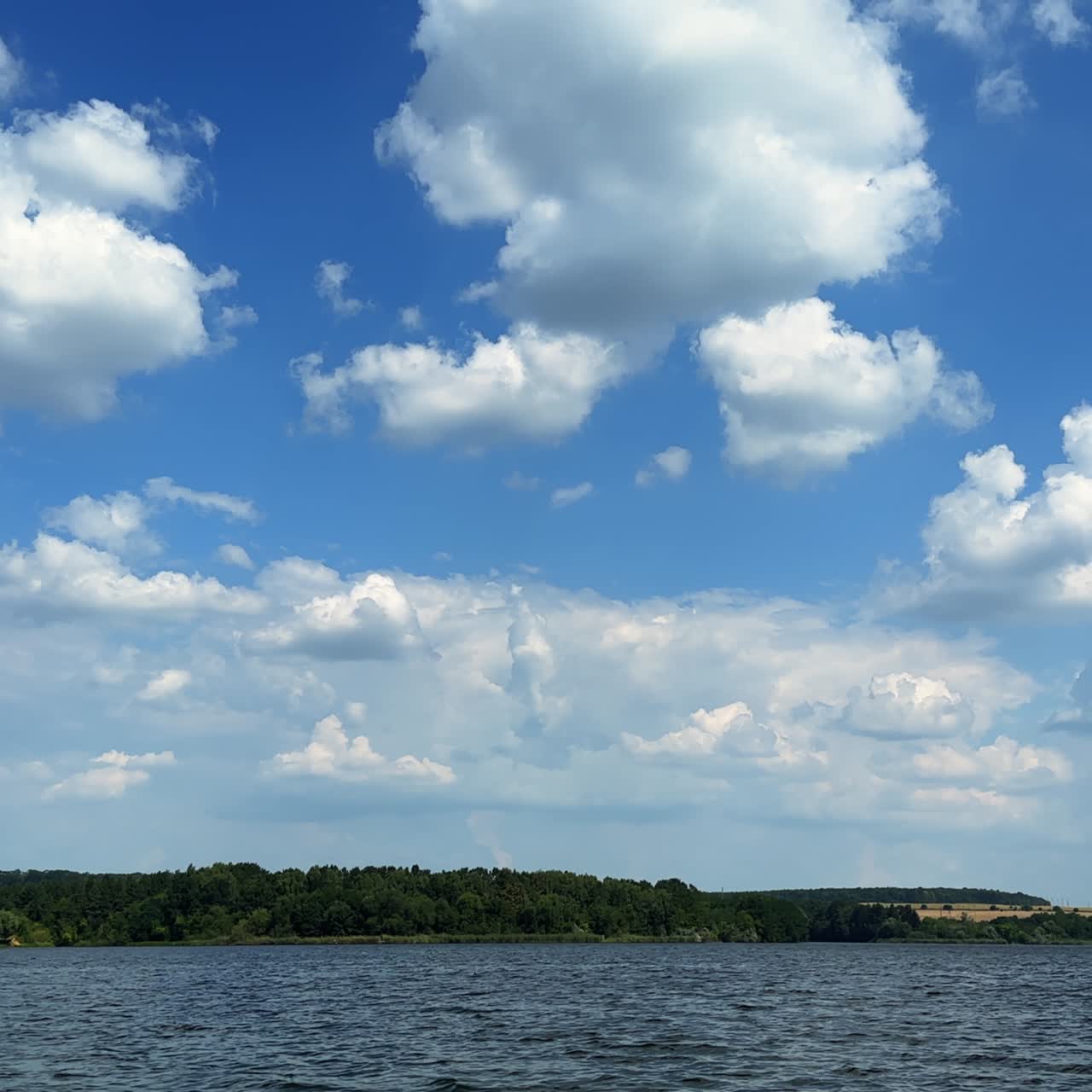 Beautiful blue summer sky with soft white clouds. Footage above the river surface on sunny day