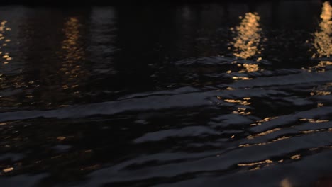 Vista-Cercana-De-Las-Olas-Del-Río-En-Barco-En-Movimiento-Por-La-Noche-Ámsterdam,-Países-Bajos