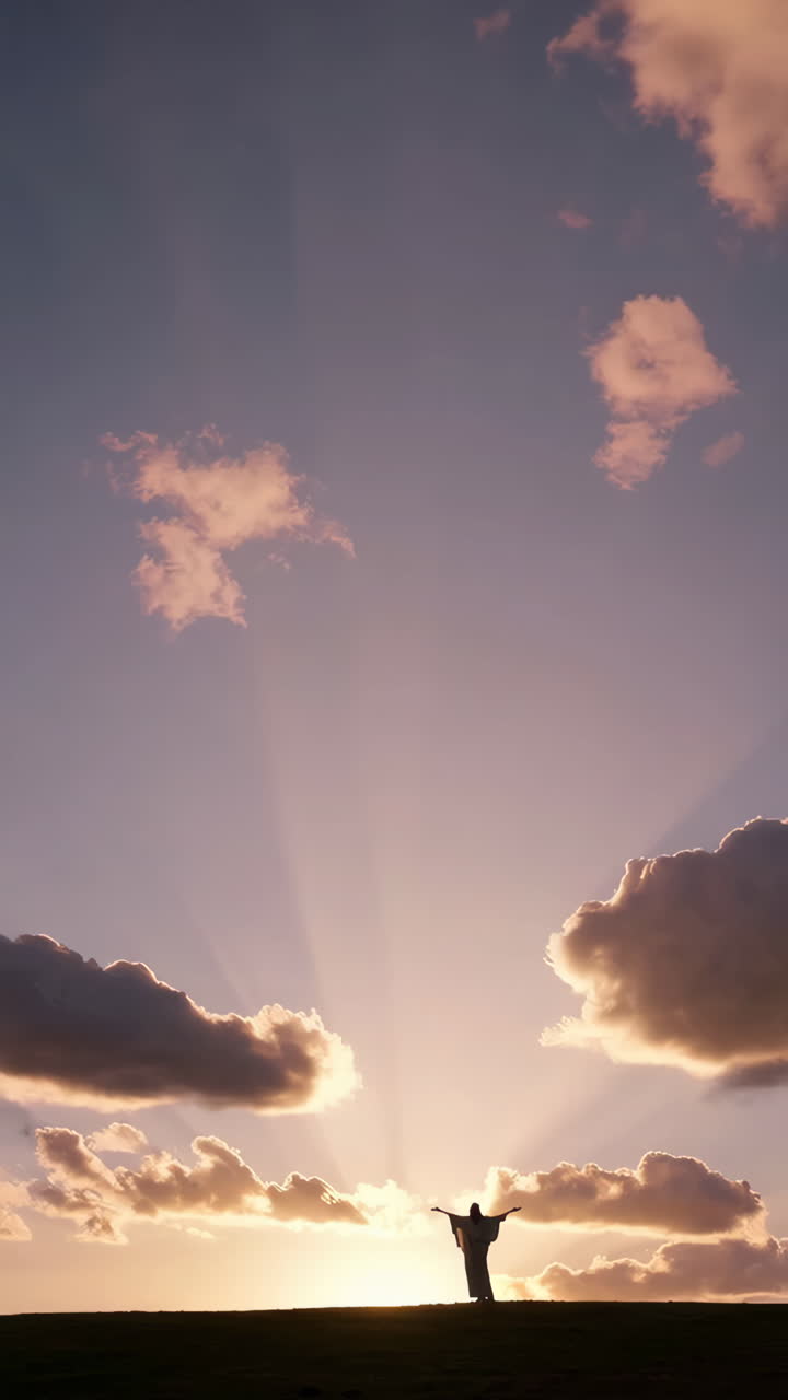 Silhouette of a person with outstretched arms against a radiant sky at sunset or sunrise.