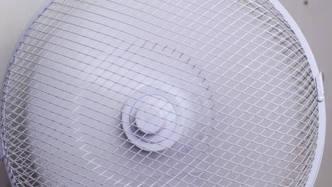 a white table fan rotating on with a white background