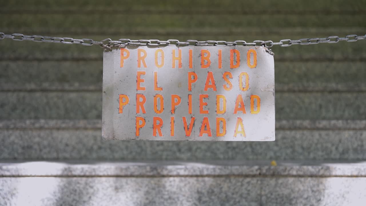 An old, faded sign and chain block a mysterious stairway. The "Prohibido El Paso" message creates a sense of suspense, secrets, and forbidden places