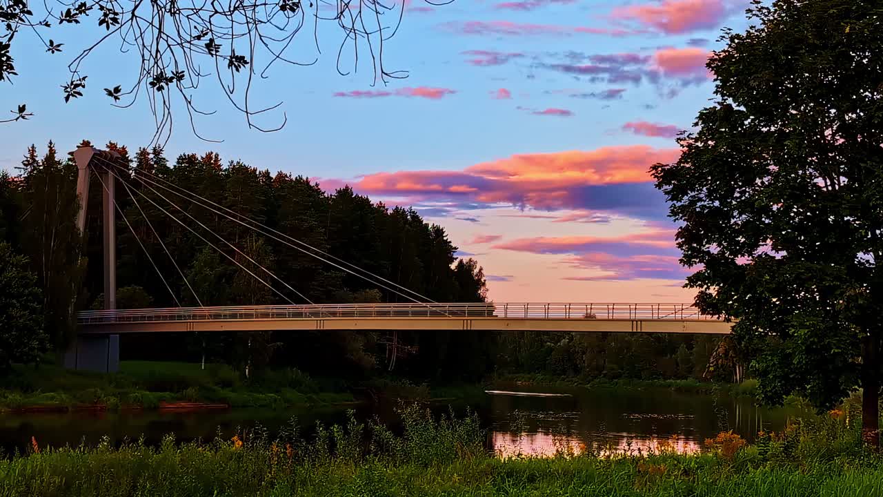 Suspension bridge over Gauja River during colorful summer sunset