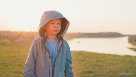 un niño está de pie en un campo mirando la puesta de sol