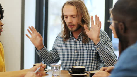 close-up view of multiethnic group of friends talking sitting at a table in a cafe