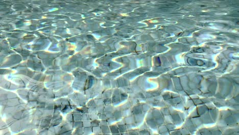 sunlight making abstract patterns on the reflective surface of a swimming pool - background texture