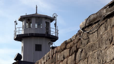 guard tower stands behind prison wall