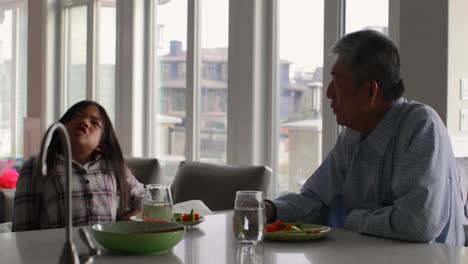 Side-view-of-cute-asian-granddaughter-and-grandfather-interacting-with-each-other-at-dining-table-4k