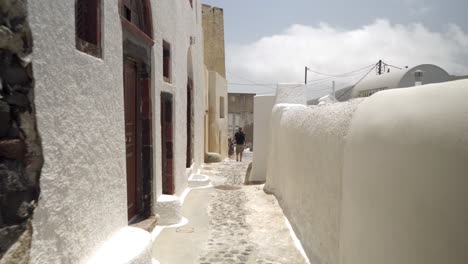 Siguiendo-A-Un-Hombre-Caminando-Por-Una-Calle-Estrecha-De-Una-Isla-Griega