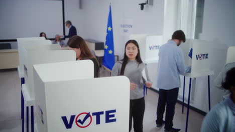 diverse voters fill out ballots in voting booths during eu elections high angle of multiethnic european people voting at polling station during eu elections diverse voters fill out ballots in voting booths election day in the european union civic duty and democracy