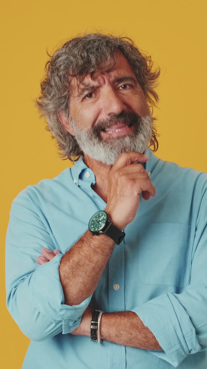 Thoughtful Mature Man Pondering and Smiling on Yellow Background