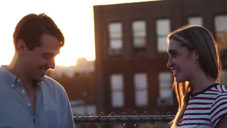 young white couple talking on a brooklyn rooftop at sunset