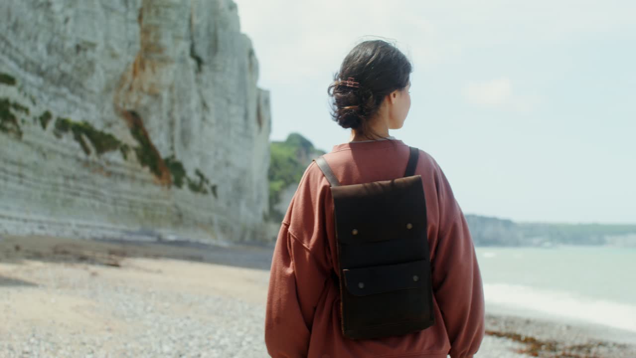 mujer caminando en la playa cerca de acantilados