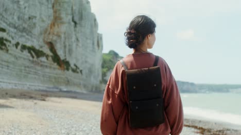 woman hiking on the beach near cliffs