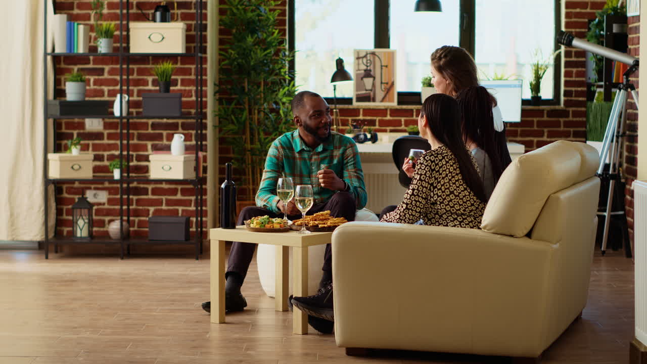Mates having lively conversation, throwing party in modern apartment living room