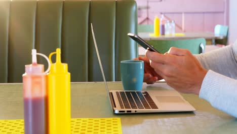 hombre usando computadora portátil y teléfono móvil mientras toma café 4k