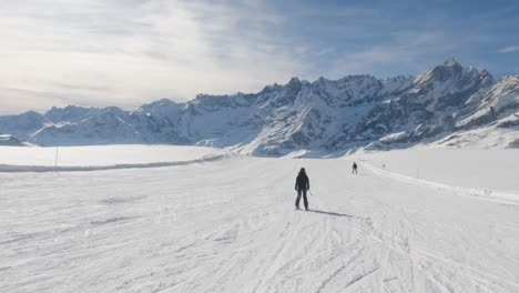 Tracking-Ansicht-Einer-Skifahrerin,-Die-Auf-Einer-Flachen-Piste-Mit-Berggipfel-Hintergrund-Fährt