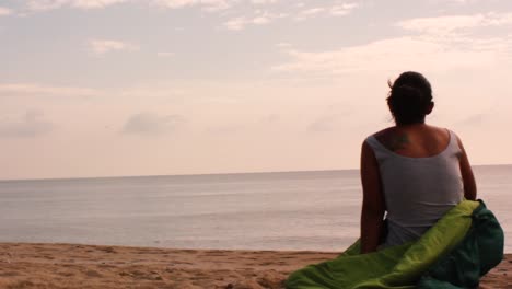 a young girl waking up at the beach in her sleeping bag