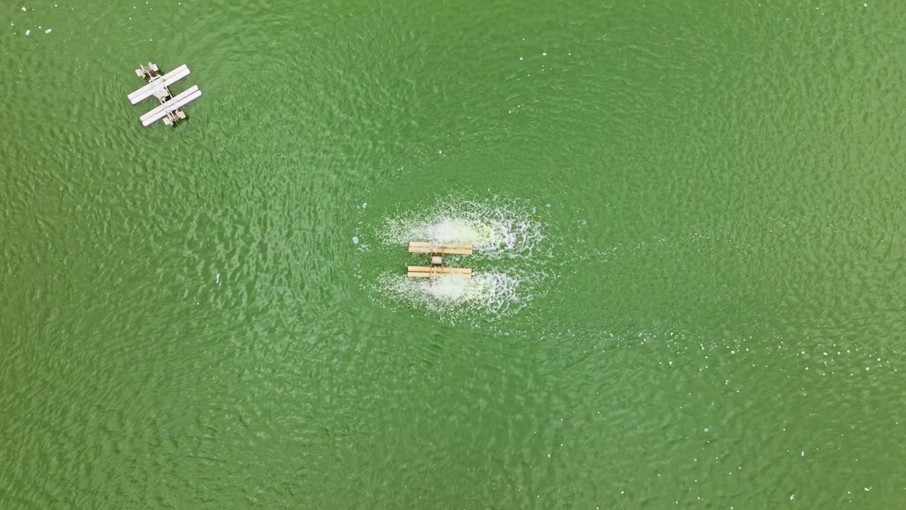 Drone ascending top-down shot showing active aeration in green fish pond