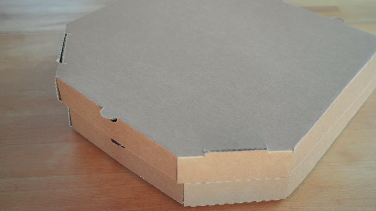 toma de primer plano de la apertura de una caja de cartón de pizza italiana recién horneada y sabrosa con salsa de pesto en una caja del cartón de la mesa