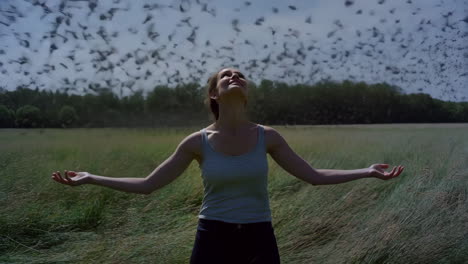 woman embracing nature in a field with a swarm of birds