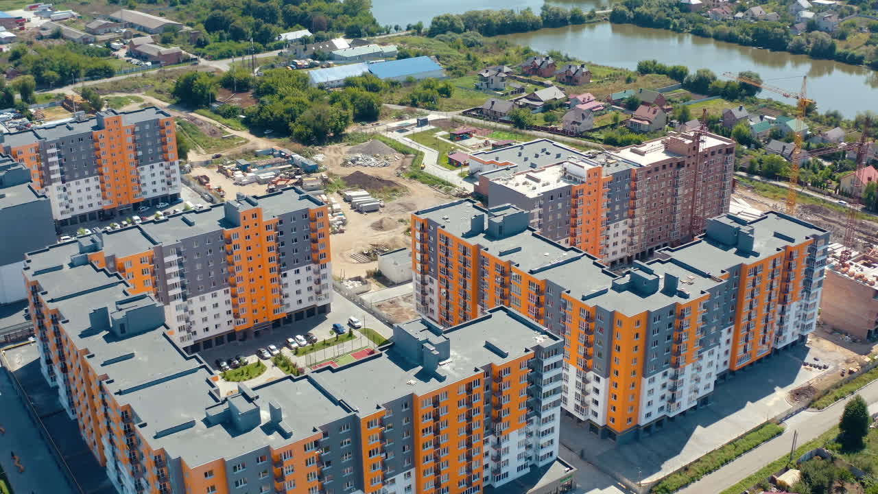 Modern urban housing on nature background. Construction site of a new residential area in the outskirts of a city. New multi-storey apartments. Aerial view.