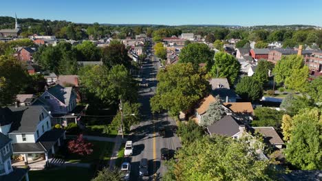 backwards aerial reveal of car driving on small town america street