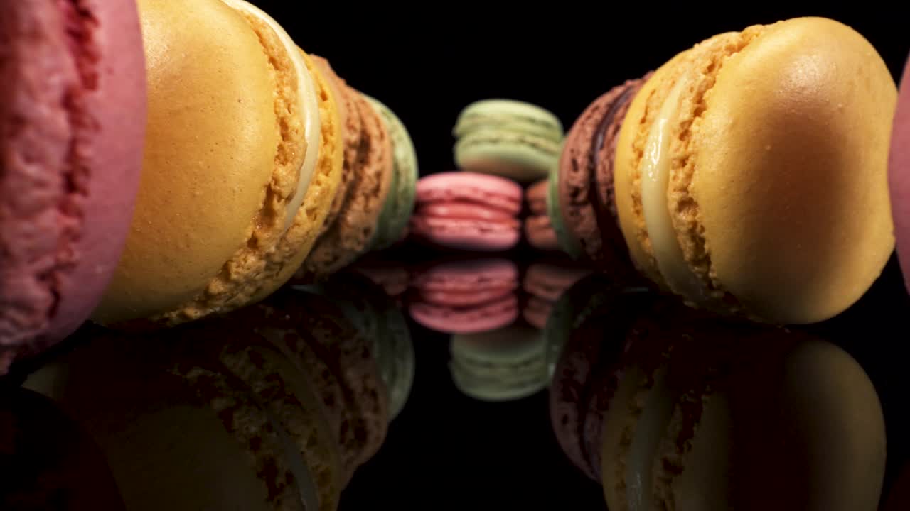 vista macro pasando macarons en vidrio reflectante negro, postres dulces y sabrosos interesante perspectiva baja