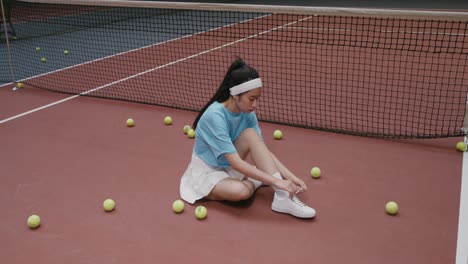 woman tying shoelaces on a tennis court