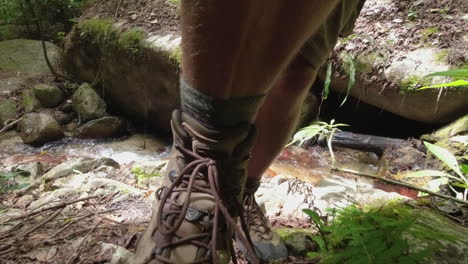 POV:-Hairy-legs-and-hiking-boots-of-man-crossing-narrow-jungle-stream