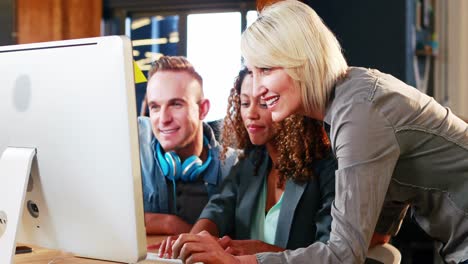 Businesswoman-interacting-with-coworkers-while-working-on-computer